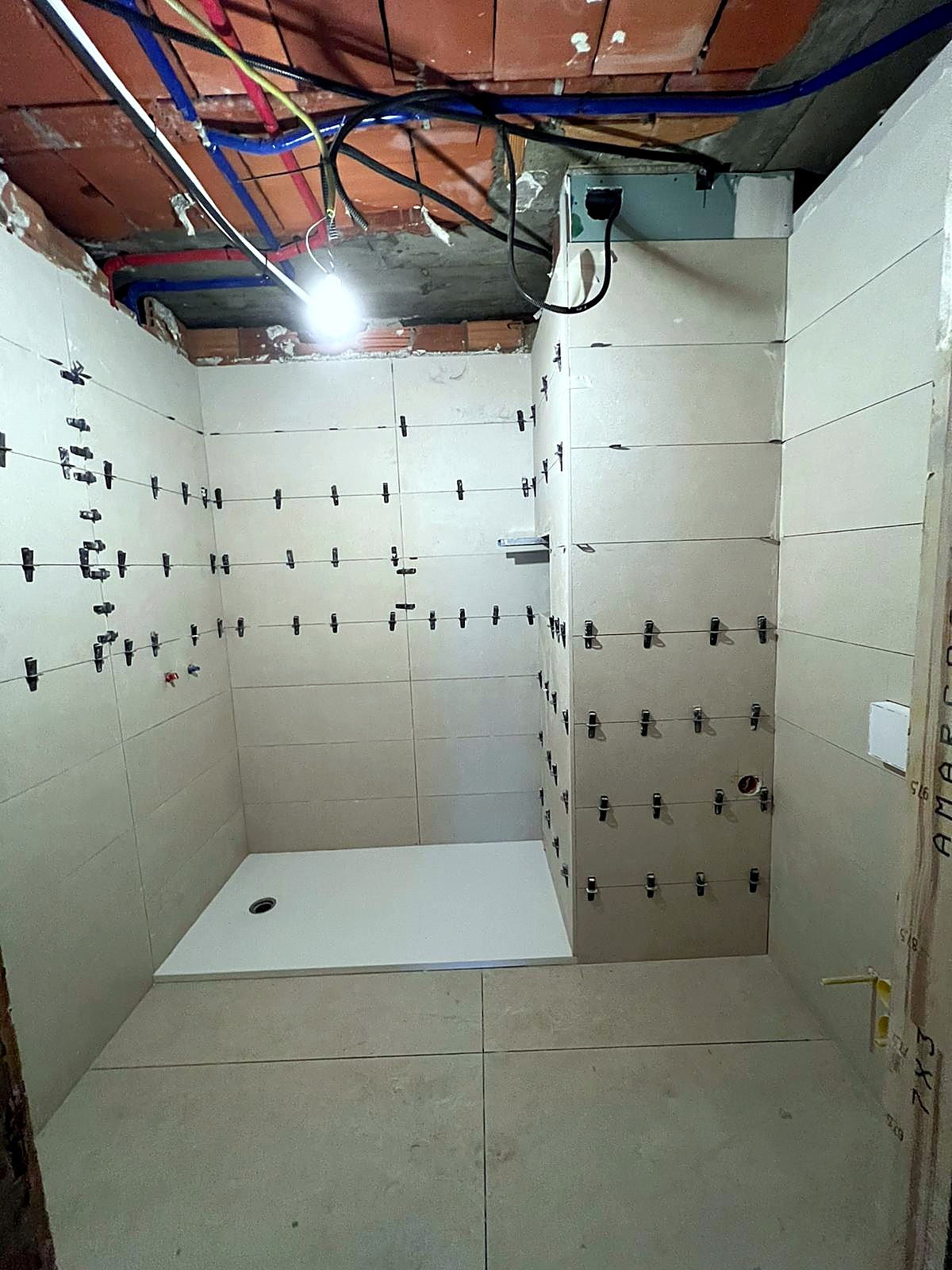 Alicatado de paredes de baño en Ourense con crucetas niveladoras: gres porcelánico formato grande sobre cementokol, plato de ducha extraplano blanco